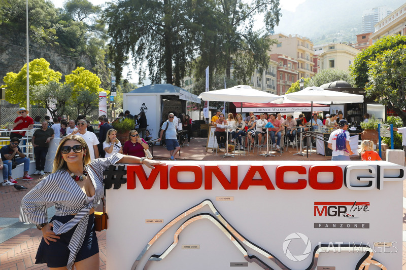 Une jeune femme pose à côté d'un panneau du Grand Prix de Monaco