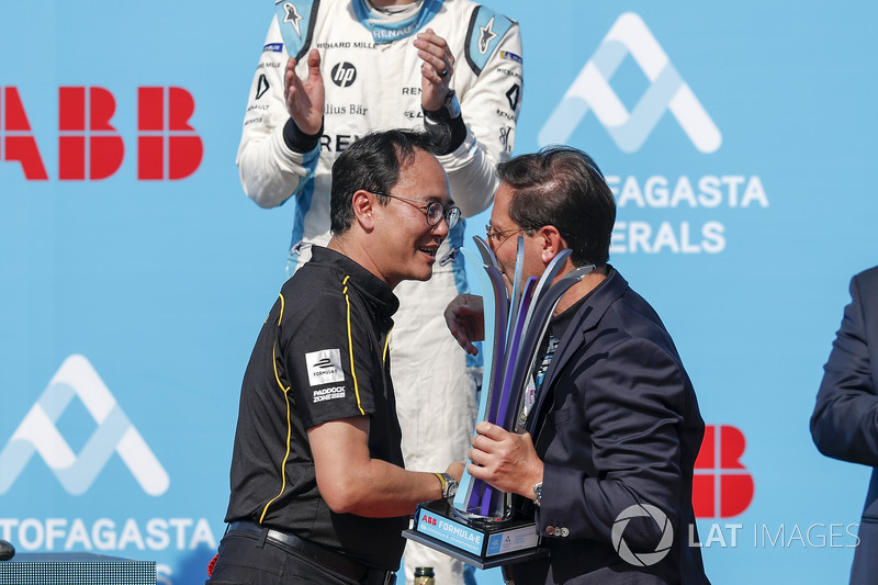 Team member collects the constructors trophy on the podium