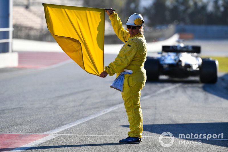 Un oficial de pista sostiene una bandera amarilla.
