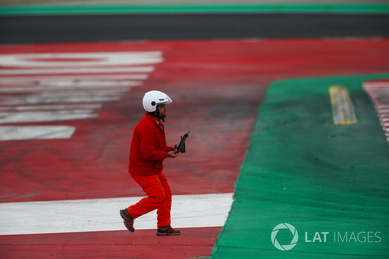 A marshal picks up a piece of debris from the track
