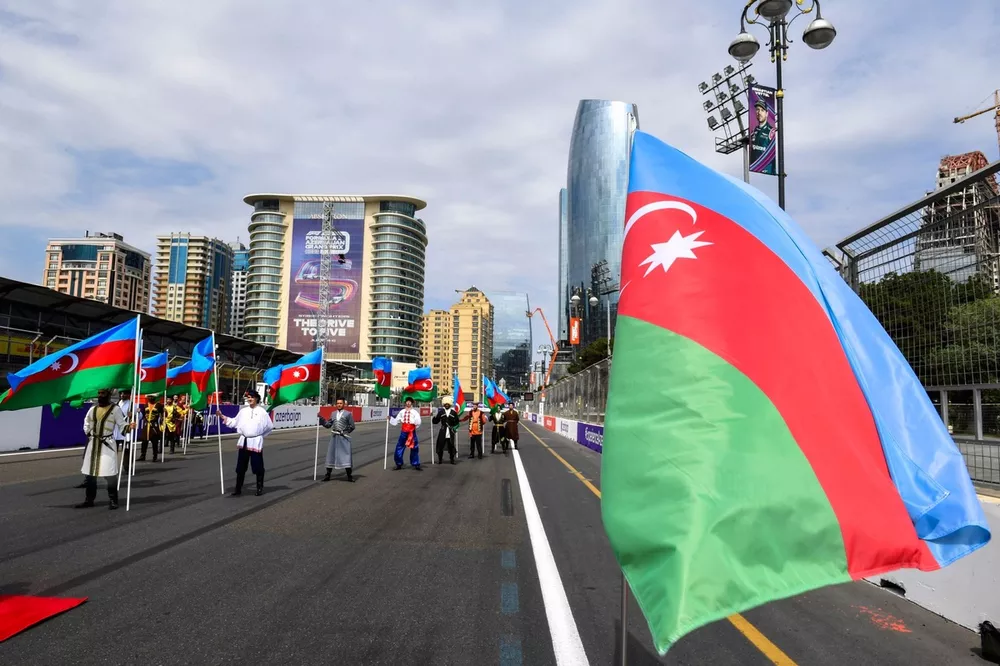Performers in traditional costume, with Azerbaijan flags on the grid