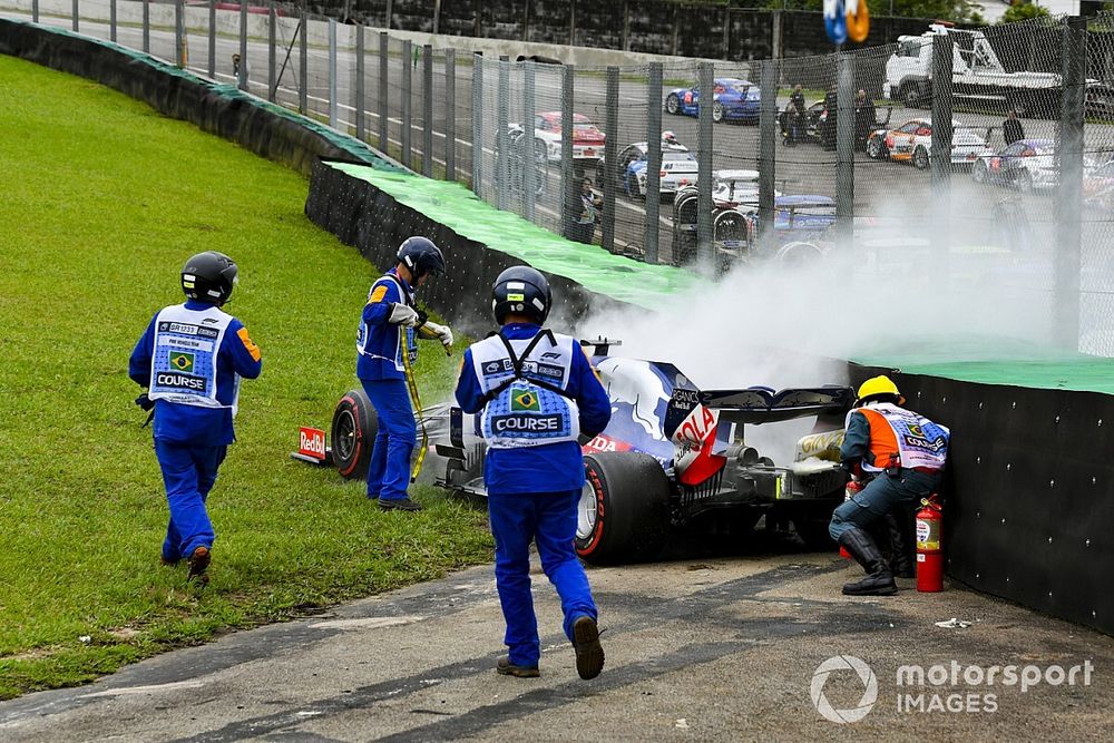 Los oficiales asisten al coche humeante de Daniil Kvyat, Toro Rosso STR14, con extintores de incendios