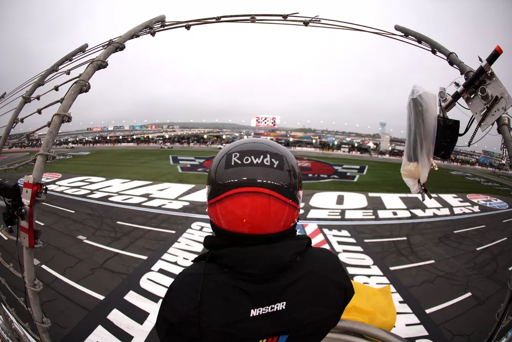 Flagman with a 'Rowdy' sticker on their helmet in tribute to Kyle Busch