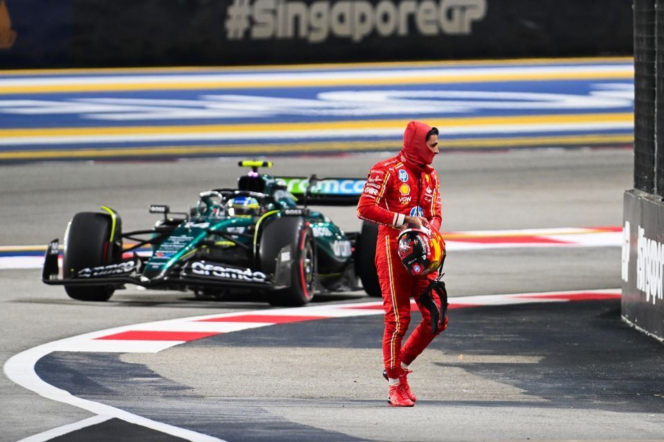 Carlos Sainz, Scuderia Ferrari, walks back to the garage after crashing out of Qualifying, as Fernando Alonso, Aston Martin AMR24, passes to head back to the pits