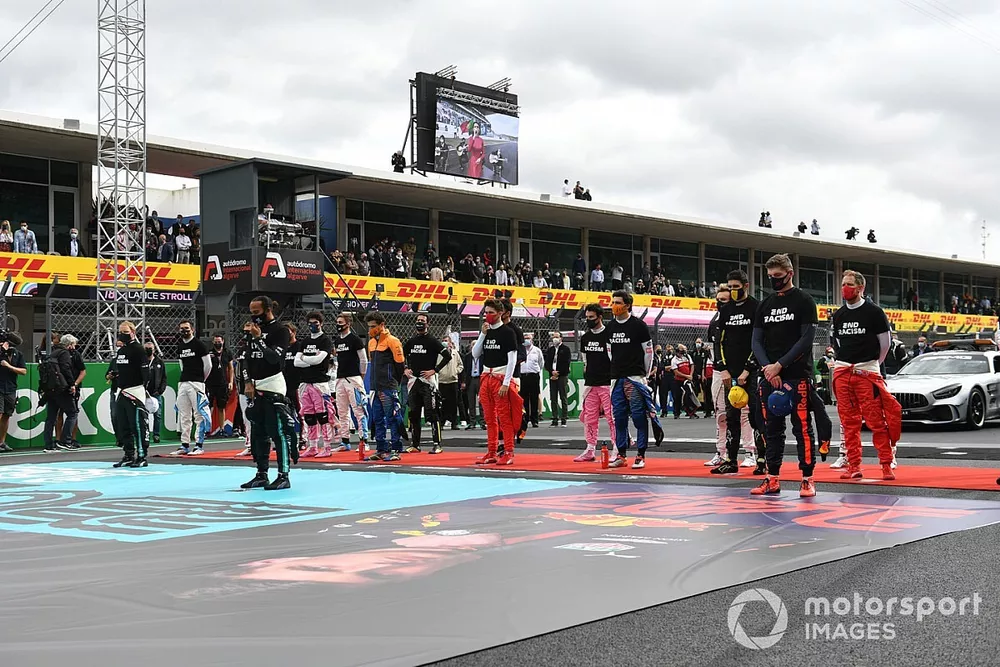 Los pilotos se ponen de pie para el himno nacional antes de la salida en sus camisetas de "End Racism".