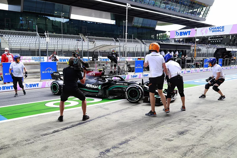 Miembros del equipo de pits de McLaren intentan asistir a Valtteri Bottas, Mercedes W12, despu&eacute;s de que hizo un trompo en el pit lane