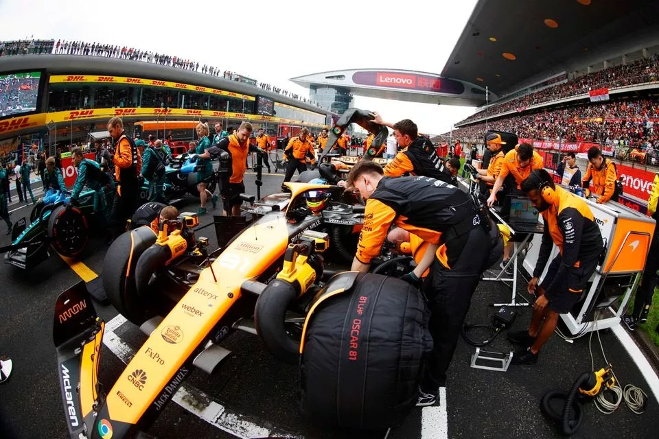 Des mécaniciens avec Oscar Piastri, McLaren MCL38 sur la grille de départ