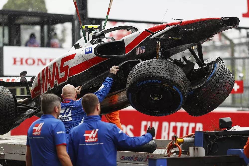Mechanics unload the damaged car of Mick Schumacher, Haas VF-22, from a flat bed truck after FP1