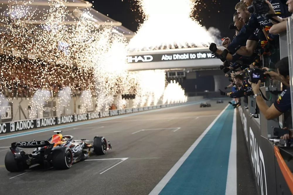 Vuurwerk verlicht de hemel als het Red Bull Racing-team Max Verstappen, Red Bull Racing RB19, 1e positie, over de streep juicht vanaf de pitmuur