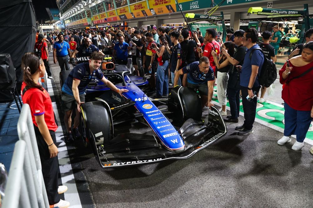 Fans watch as Williams mechanics push the car of Franco Colapinto, Williams FW46,