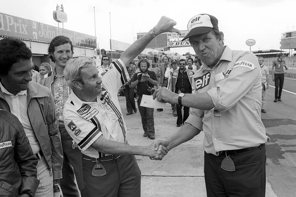 Teddy Mayer, propietario del equipo McLaren entrega un cheque a Ken Tyrrell, propietario del equipo Tyrrell despu&eacute;s de perder una competencia de cambio de neum&aacute;ticos en los pits