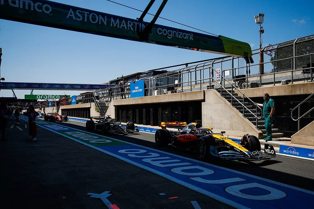 Oscar Piastri, McLaren MCL60, Lewis Hamilton, Mercedes F1 W14, en el pit lane