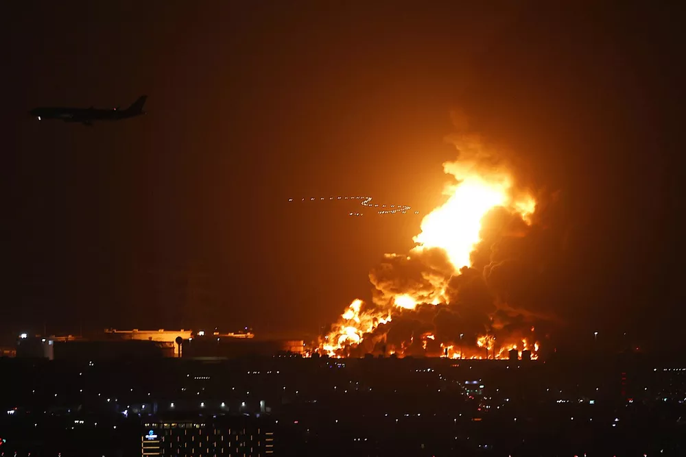 An airliner is silhoutted by a fire in Jeddah beyond the circuit