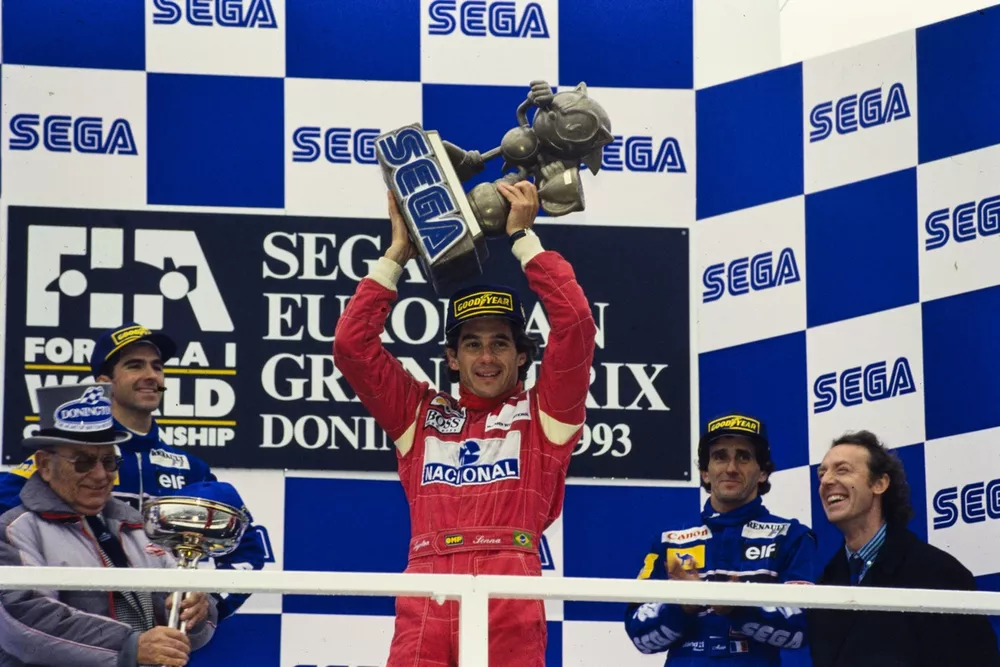 Ayrton Senna, 1st position, holds the Sega Sonic the Hedgehog trophy aloft on the podium