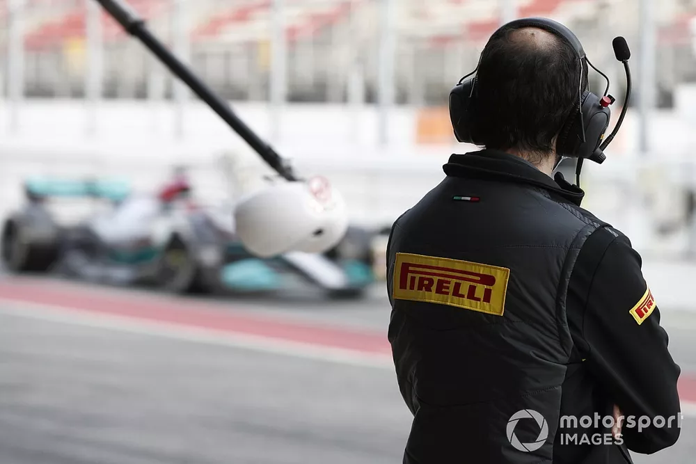 A Pirelli technician watches as George Russell, Mercedes W13, passes in the pit lane