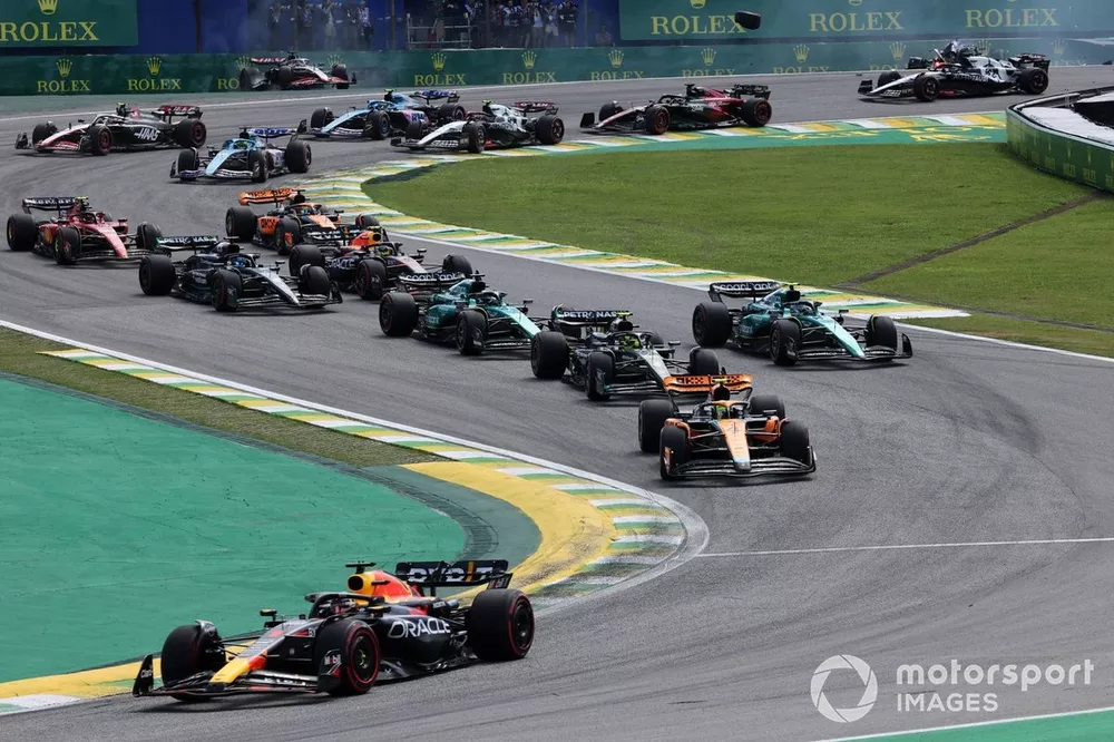 Max Verstappen, Red Bull Racing RB19, Lando Norris, McLaren MCL60 en de rest van het veld als Kevin Magnussen, Haas VF-23, Alex Albon, Williams FW45, crashen