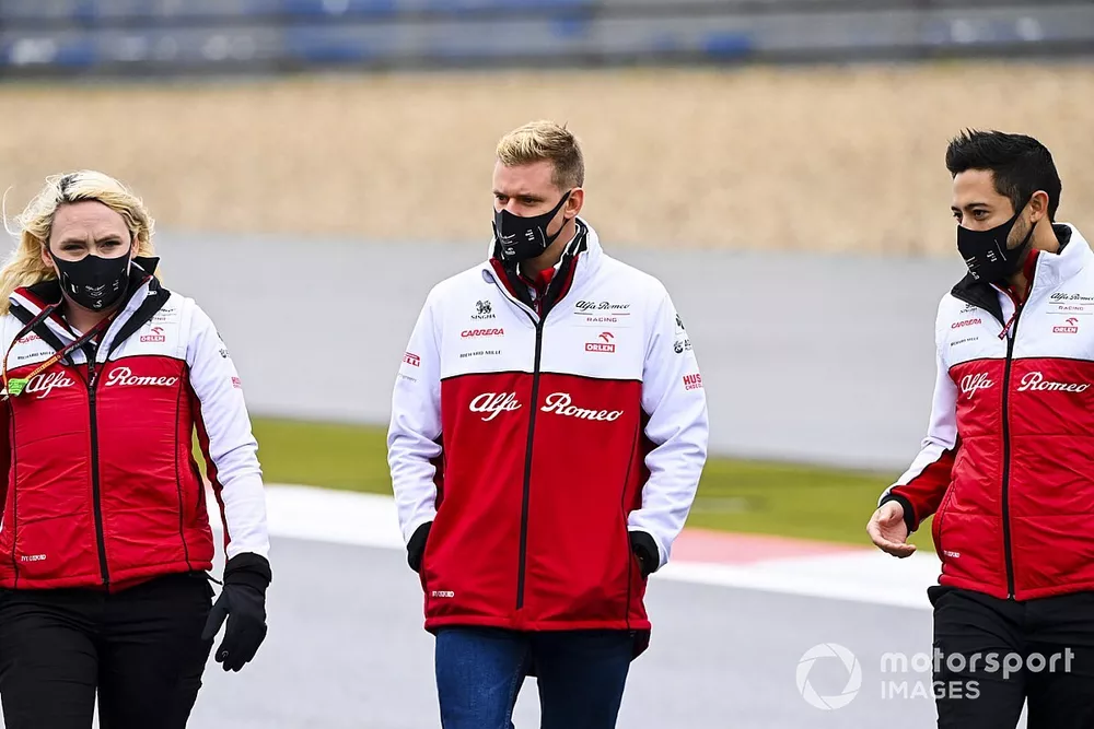 Mick Schumacher, Alfa Romeo, recorre la pista con miembros del equipo