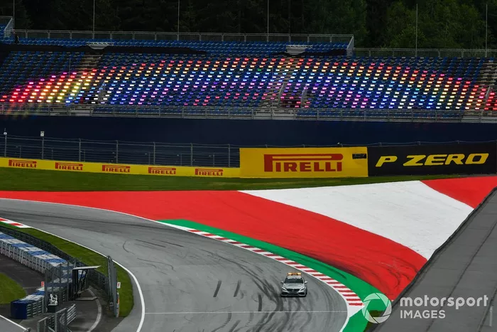 Los pilotos del coche de seguridad de Mercedes pasan por una tribuna vacía iluminada por luces multicolores
