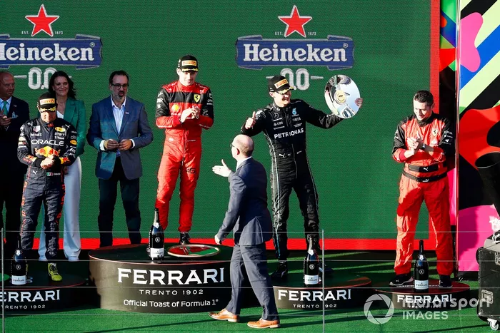 Sergio Pérez, Red Bull Racing, segundo, Charles Leclerc, Ferrari, primero, George Russell, Mercedes-AMG, tercero, y el representante de Ferrari en el podio