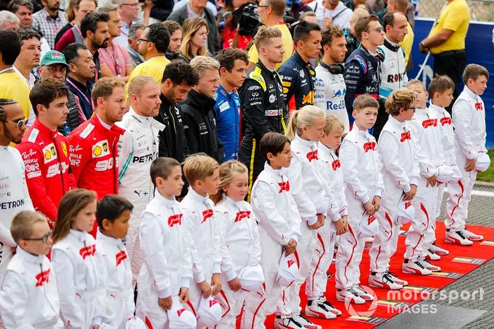 The drivers join the Grid Kid mascots for the national anthem prior to the start