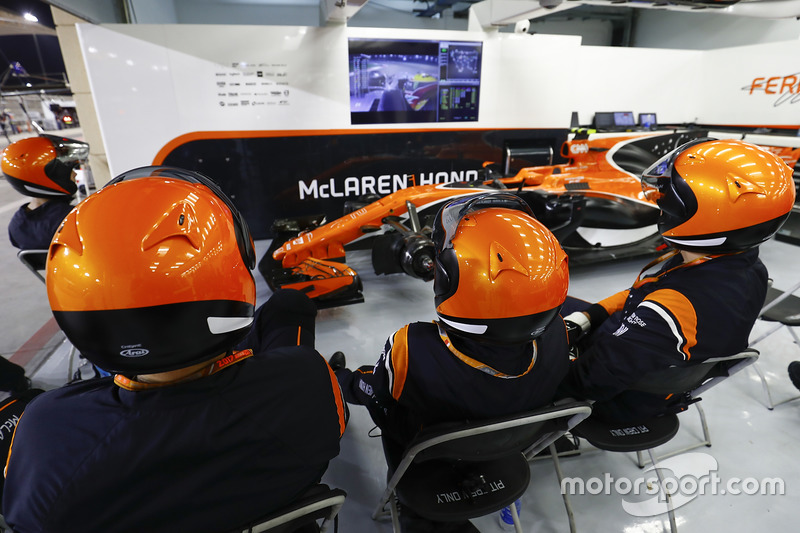 Los mecánicos de McLaren ven la carrera en el garaje con el auto de Stoffel Vandoorne, McLaren MCL32