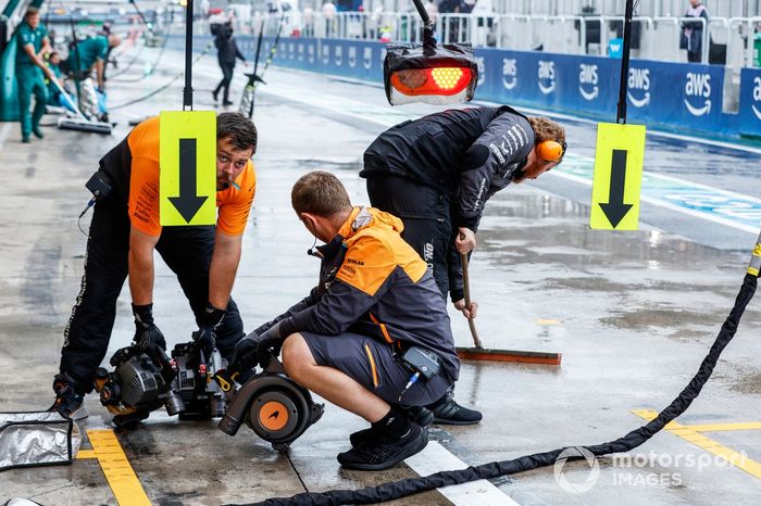 Mecánicos del equipo McLaren F1 utilizan secadores para secar el box en el pit lane 