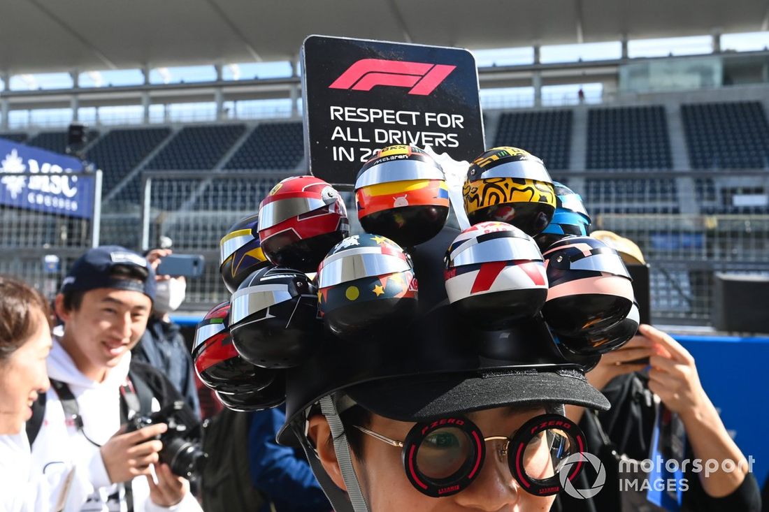 Um adepto com um boné com os capacetes dos pilotos nas boxes