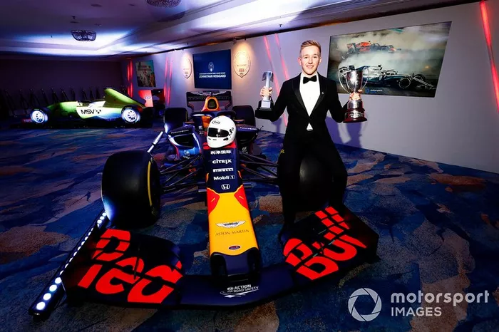 Il vincitore dell'Aston Martin Autosport BRDC Young Driver Award Johnathan Hoggard festeggia con gli amici e la famiglia con il trofeo e l'assegno vicino alla Red Bull Racing RB15