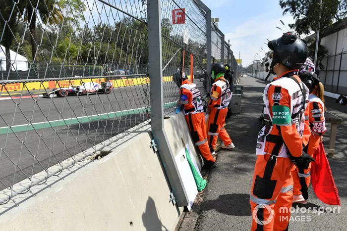 Oficiales de pista observan el paso de Mick Schumacher, Haas VF-21