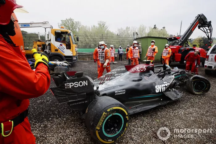 Los oficiales de pista despejan el coche dañado de Valtteri Bottas, Mercedes W12, de la trampa de grava