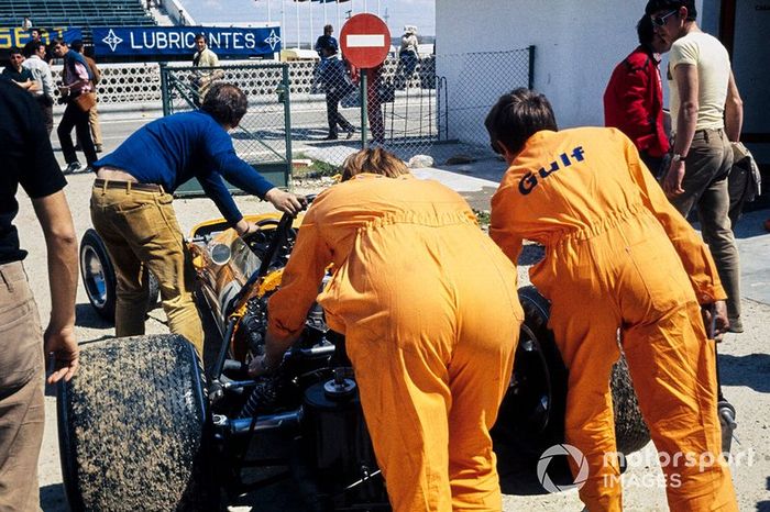 Los mecánicos empujan el monoplaza de Bruce McLaren, McLaren M14A Ford a la pista