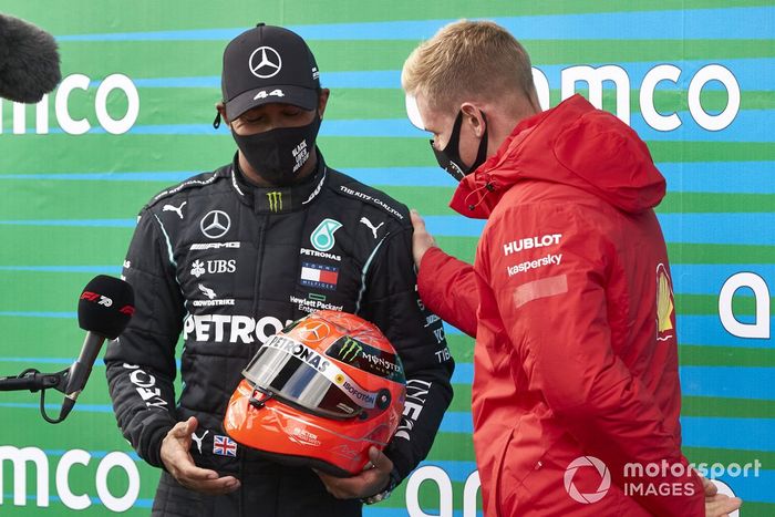 Mick Schumacher entrega a Lewis Hamilton, Mercedes-AMG F1, el casco de su padre después de que el piloto de Mercedes igualara el récord de Michael Schumacher de 91 victorias en carreras