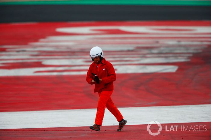 Un mariscal recoge un pedazo de escombros de la pista