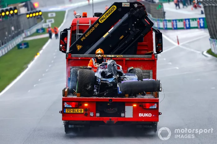 Un comisario con el coche dañado de Logan Sargeant, Williams FW46, en un camión