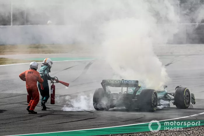 Oficiales de pista asisten a Sebastian Vettel, Aston Martin AMR22, después de que un fallo técnico produzca humo
