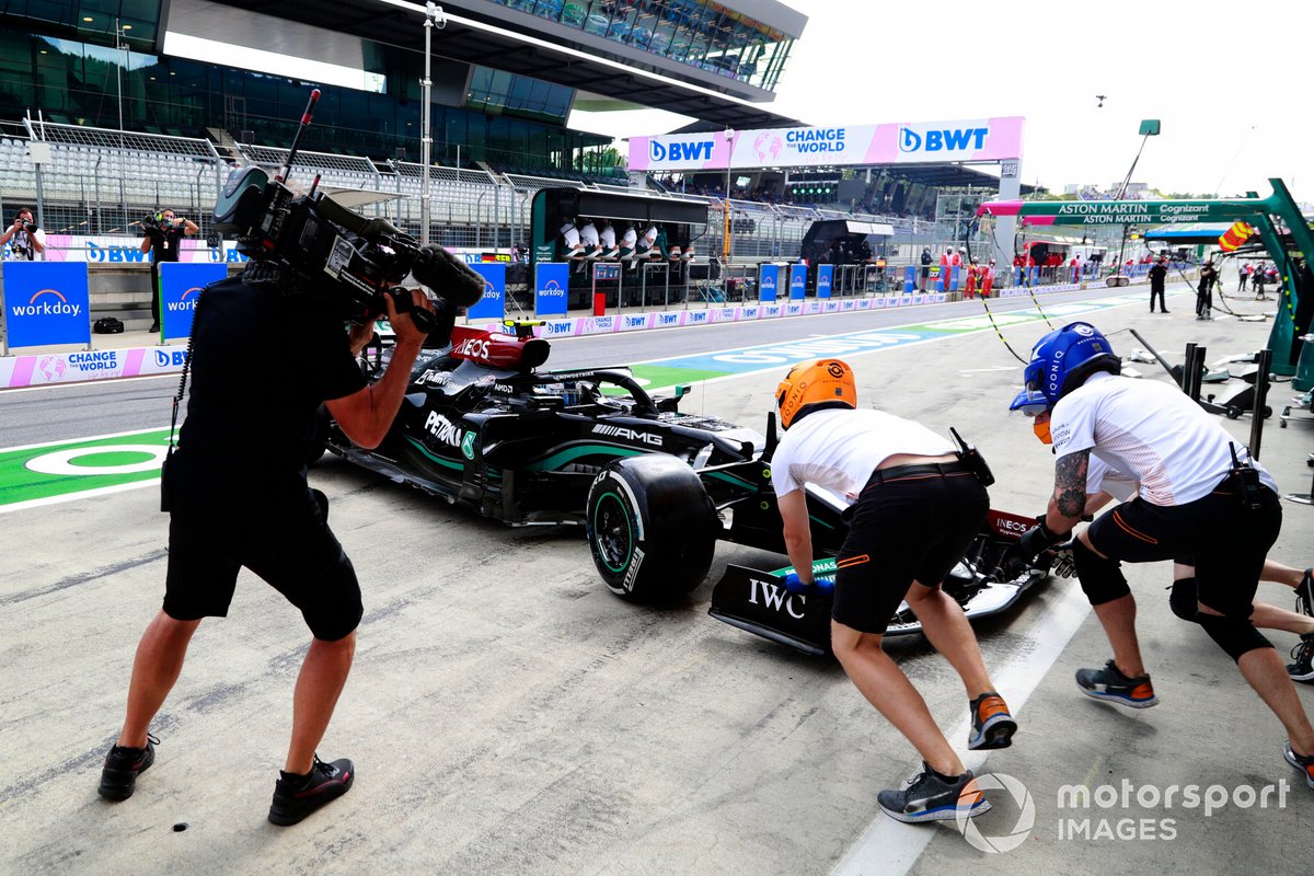 McLaren pit crew members attempt to assist Valtteri Bottas, Mercedes W12, in the pitlane