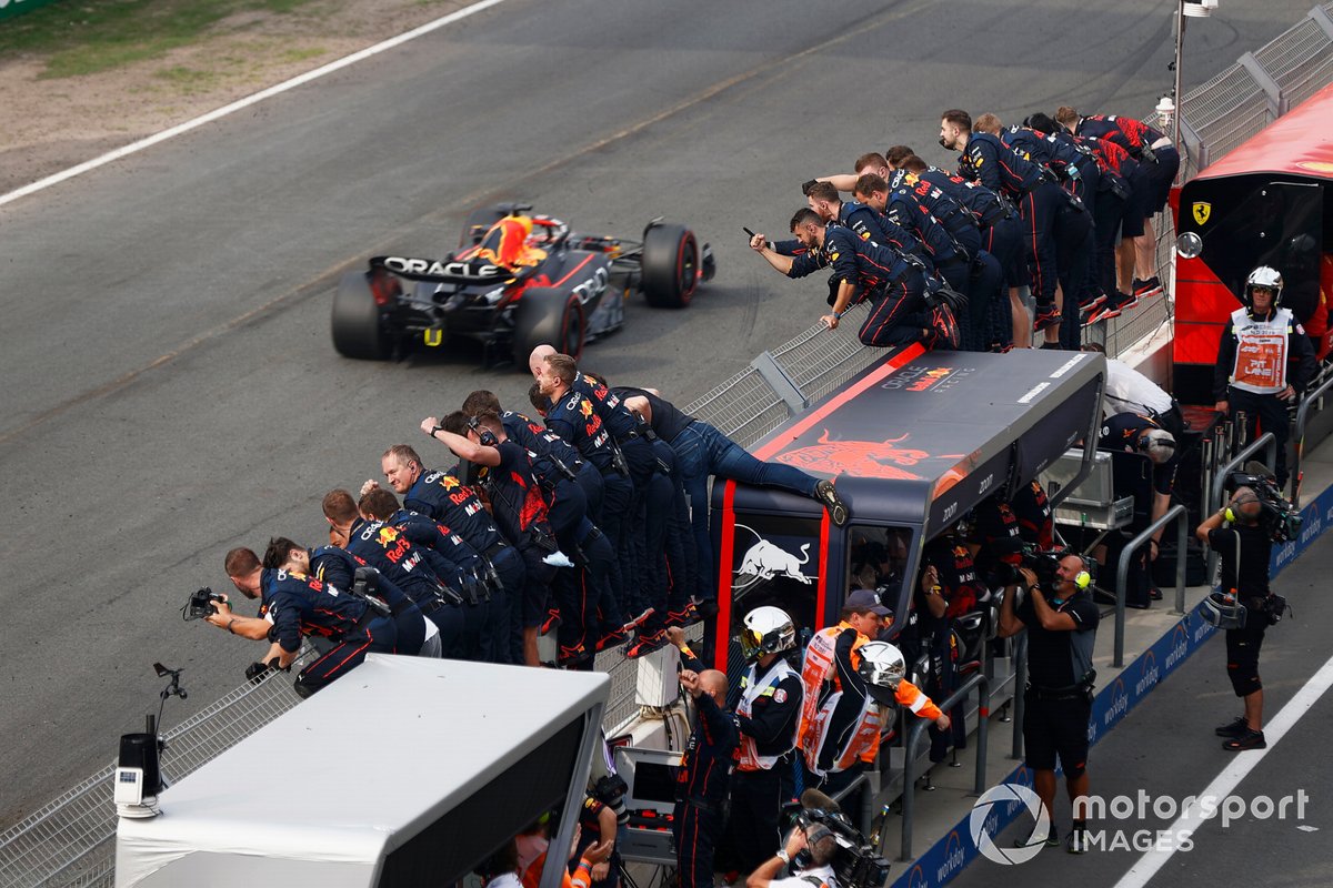 The team celebrate on the pit wall as Max Verstappen, Red Bull Racing RB18, crosses the line and takes the chequered flag