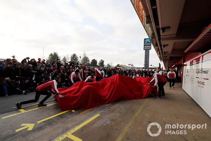 Les mécaniciens Alfa Romeo Racing avec l'Alfa Romeo Racing C38 sous un drap
