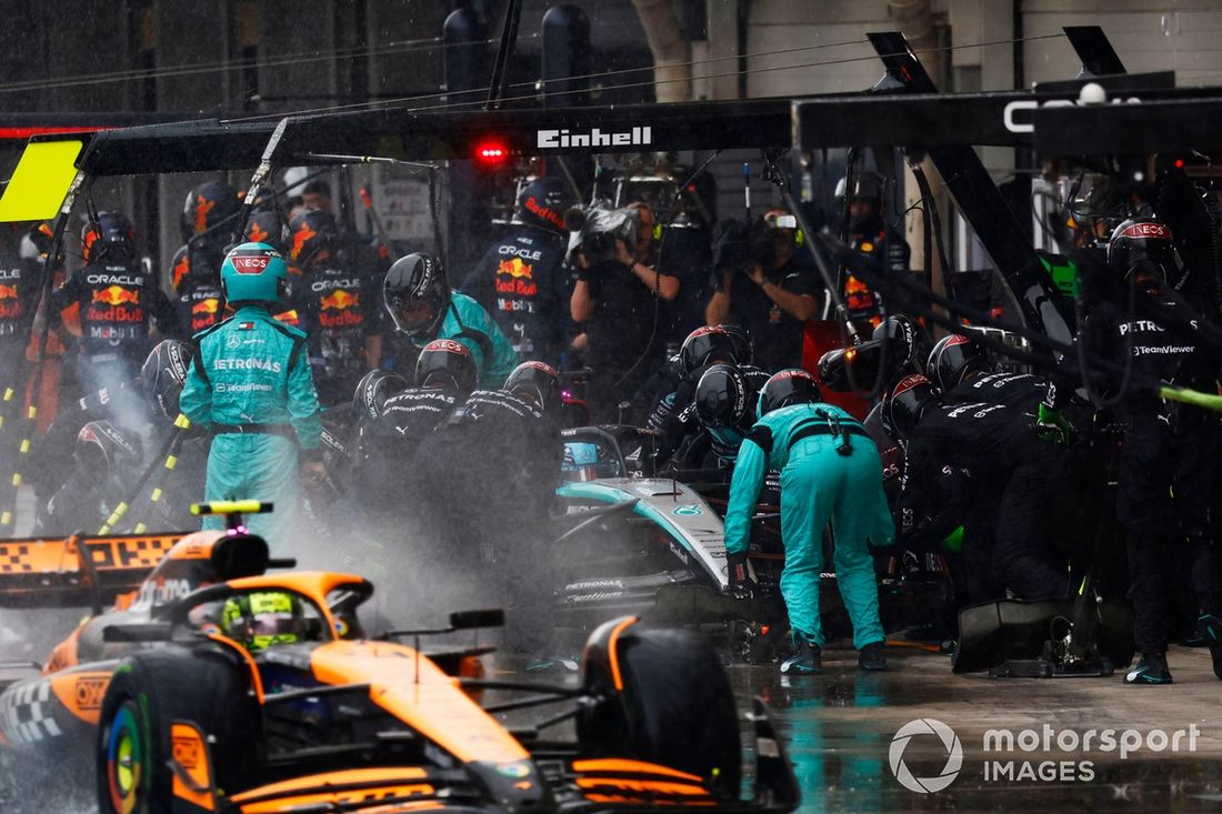 George Russell, Mercedes F1 W15, hace una parada en boxes mientras Lando Norris, McLaren MCL38, pasa por el pit lane.