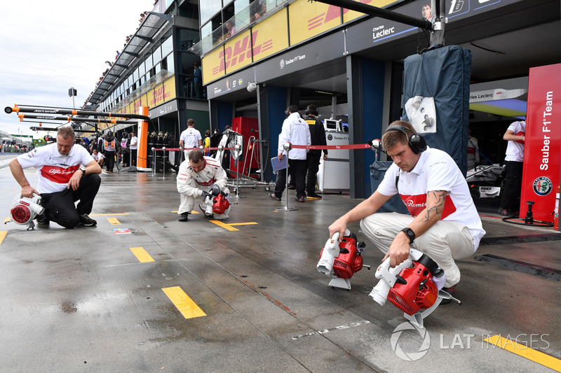 Les mécaniciens Sauber assèchent l'emplacement dans les stands