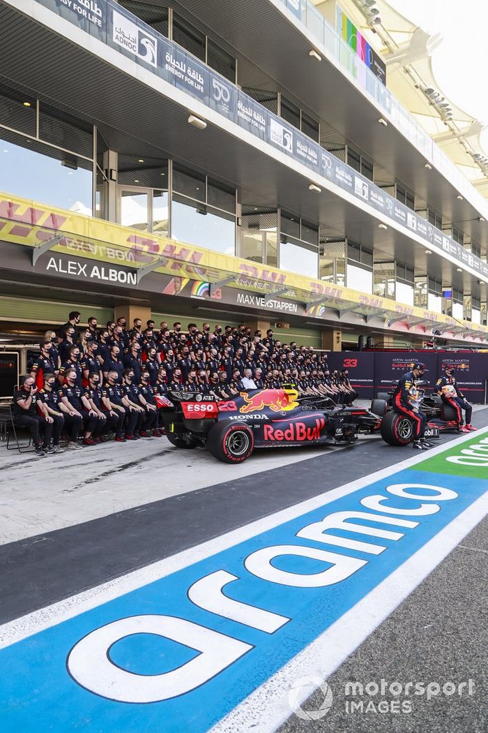 Foto de grupo del equipo Red Bull con Alex Albon, Max Verstappen y sus coches en el pitlane
