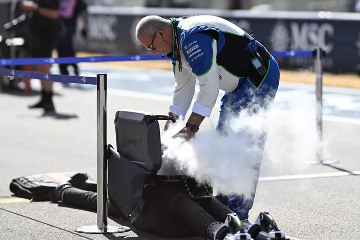 Racing Bulls team member on the grid with cooling equipment