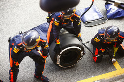 Red Bull mechanics wait outside of their garage with a Pirelli tyre