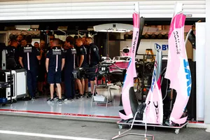 Des mécaniciens rassemblés dans le garage de Force India près de la monoplace de Sergio Perez Force India VJM11