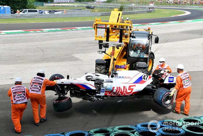 Los oficiales retiran el coche dañado de Mick Schumacher, Haas VF-21, de una barrera de neumáticos tras su accidente en la FP3