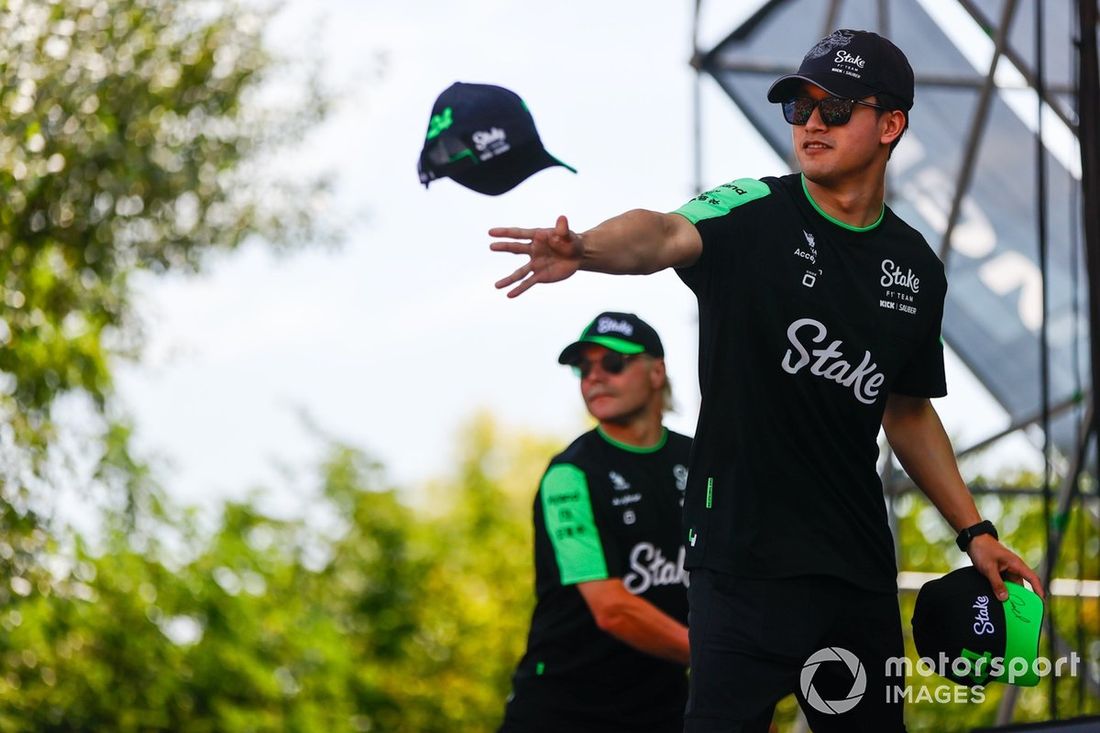 Zhou Guanyu, Stake F1 Team Kick Sauber, rzuca kibicom czapki. Valtteri Bottas, Stake F1 Team Kick Sauber, stoi z tyłu