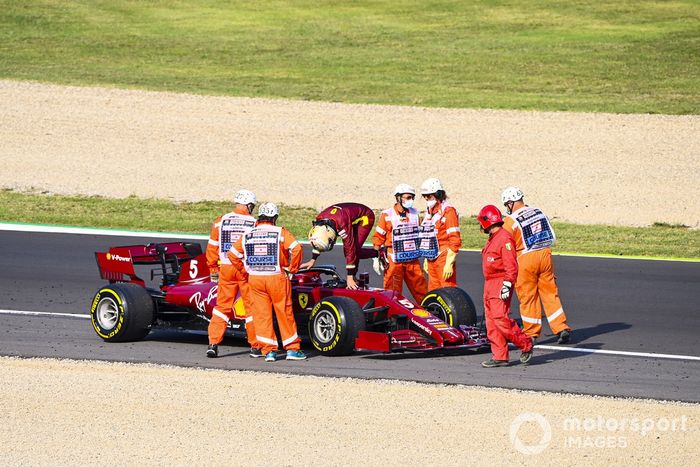 Los oficiales asisten mientras Sebastian Vettel, Ferrari SF1000 se detiene en la pista