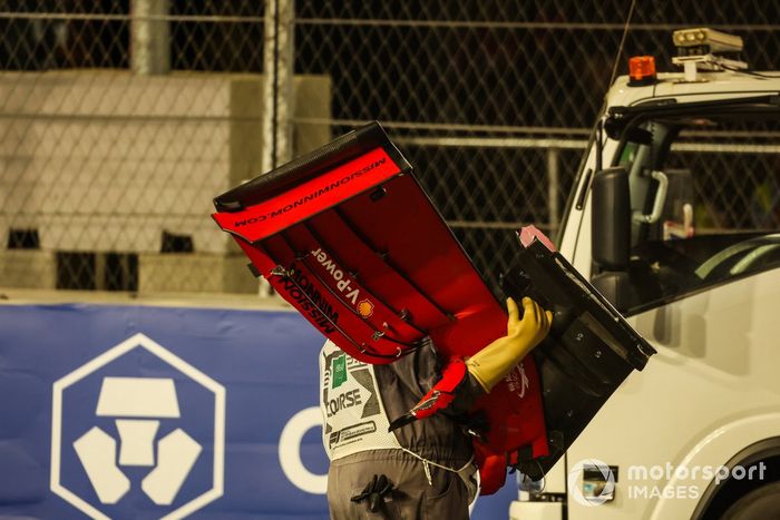 Un oficial de pista retira el alerón delantero del coche de Charles Leclerc, Ferrari SF21, del circuito