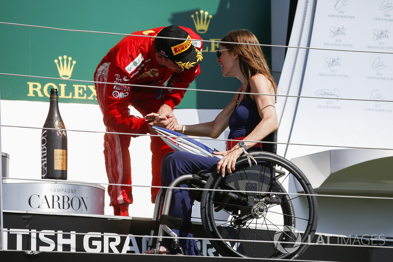 Third place Kimi Raikkonen, Ferrari, receives his trophy from Nathalie McGoin on the podium