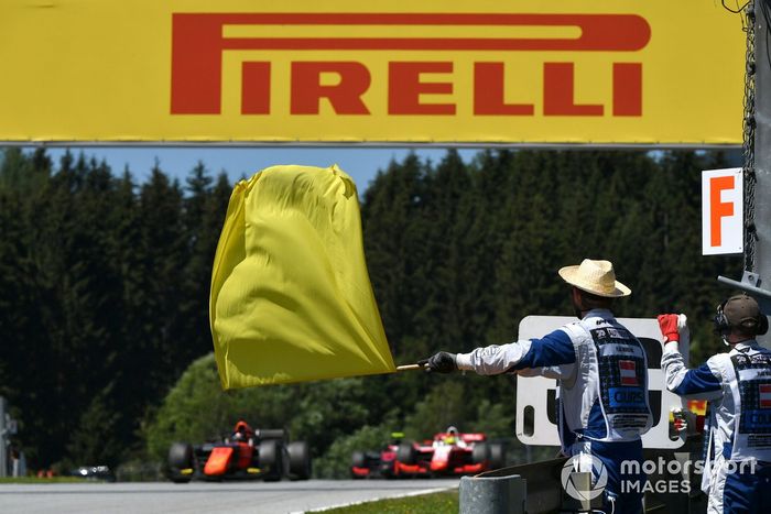 Un comisario con la bandera amarilla con Nobuharu Matsushita, MP Motorsport, al fondo